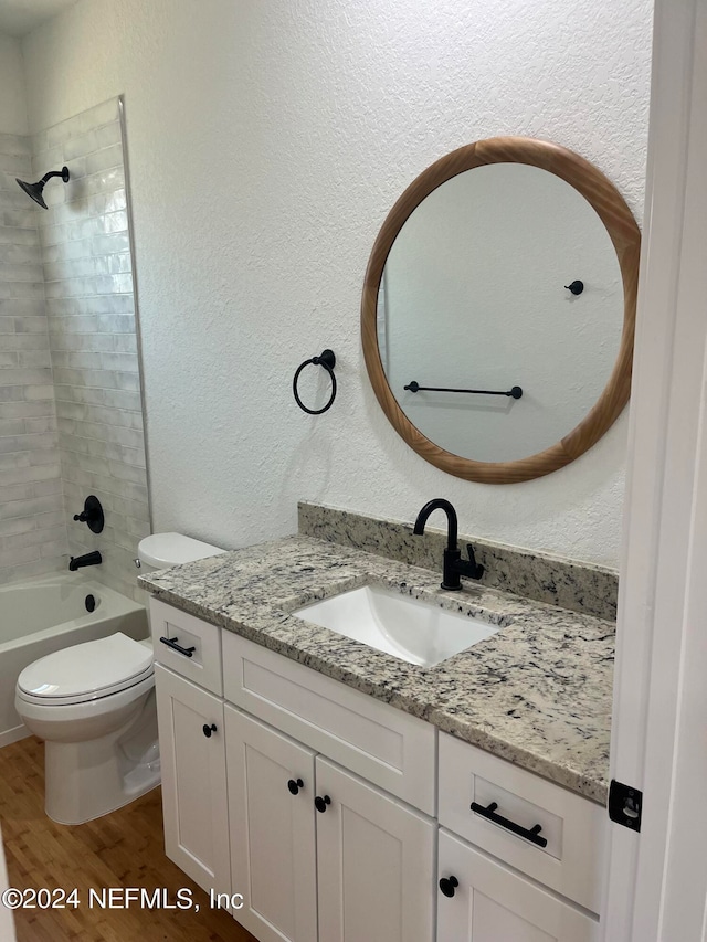 full bathroom featuring wood-type flooring, vanity, toilet, and tiled shower / bath