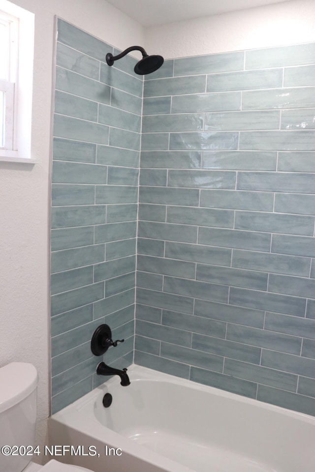 bathroom with tiled shower / bath combo and toilet