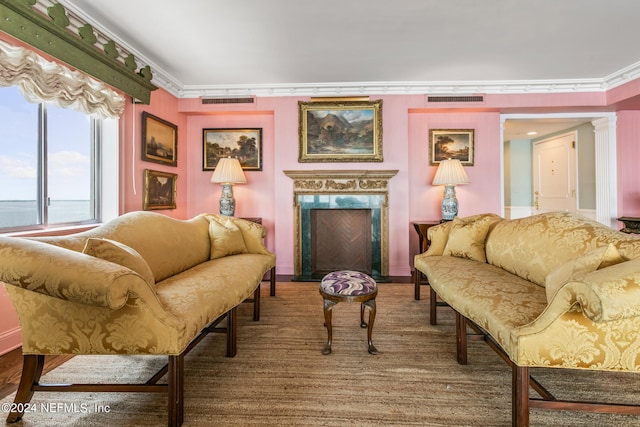 living room featuring a high end fireplace, a water view, ornate columns, and ornamental molding