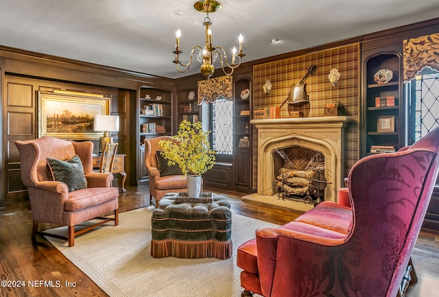 living area featuring a large fireplace, dark hardwood / wood-style flooring, built in features, and an inviting chandelier