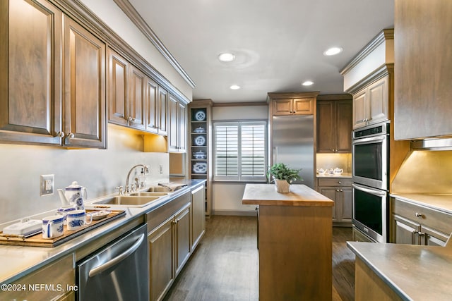 kitchen featuring sink, ornamental molding, appliances with stainless steel finishes, butcher block countertops, and a kitchen island