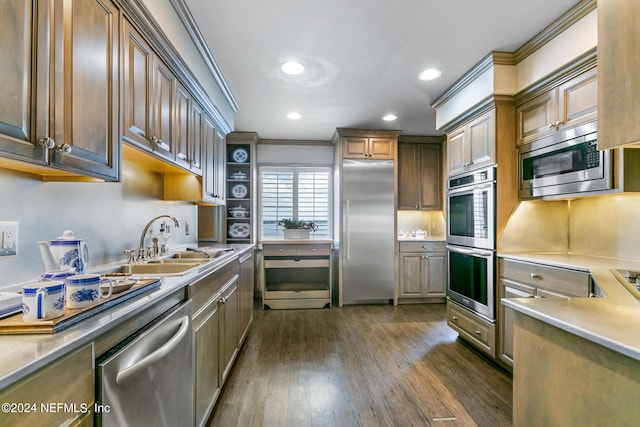 kitchen with built in appliances, dark hardwood / wood-style floors, crown molding, and sink