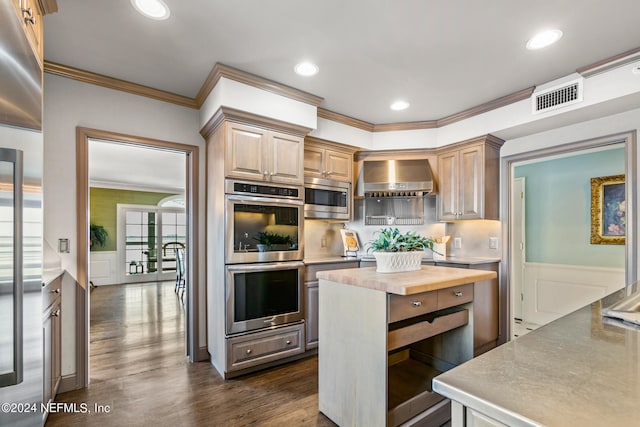 kitchen with stainless steel appliances, crown molding, wall chimney range hood, light brown cabinets, and butcher block counters