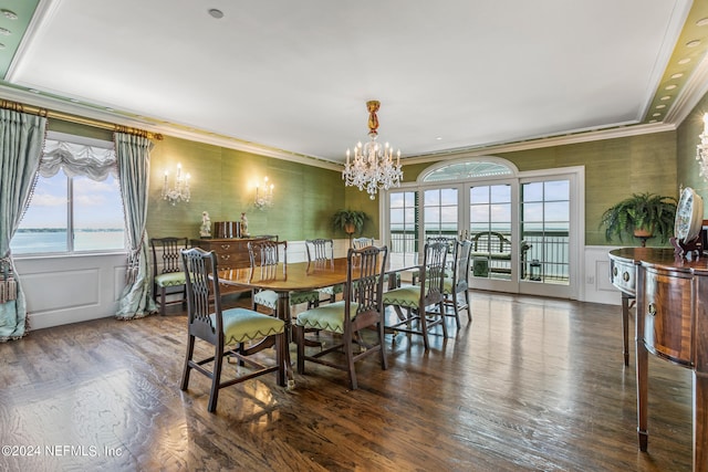 dining space featuring crown molding, dark hardwood / wood-style flooring, a water view, and an inviting chandelier