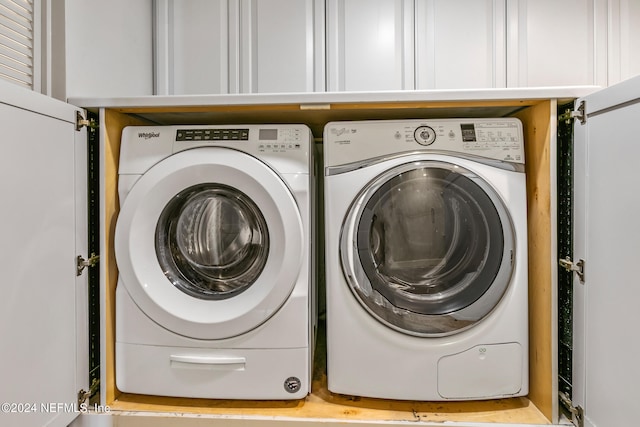 laundry room featuring washer and clothes dryer and cabinets