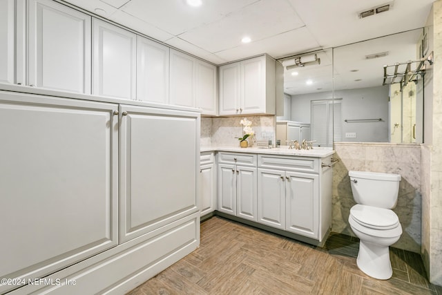 bathroom with parquet flooring, vanity, and toilet