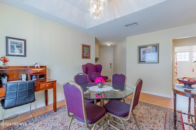 dining area with a notable chandelier, a textured ceiling, and wood-type flooring