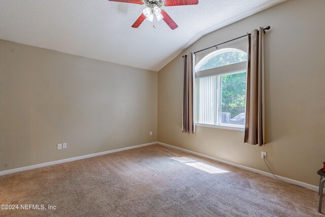 carpeted empty room with vaulted ceiling, ceiling fan, and a textured ceiling