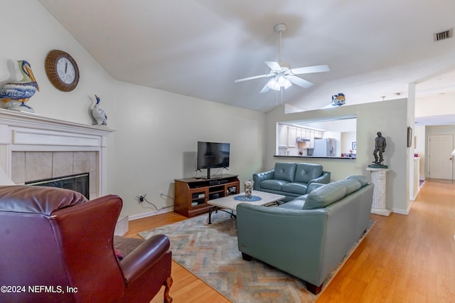 living room with light hardwood / wood-style floors, lofted ceiling, ceiling fan, and a fireplace