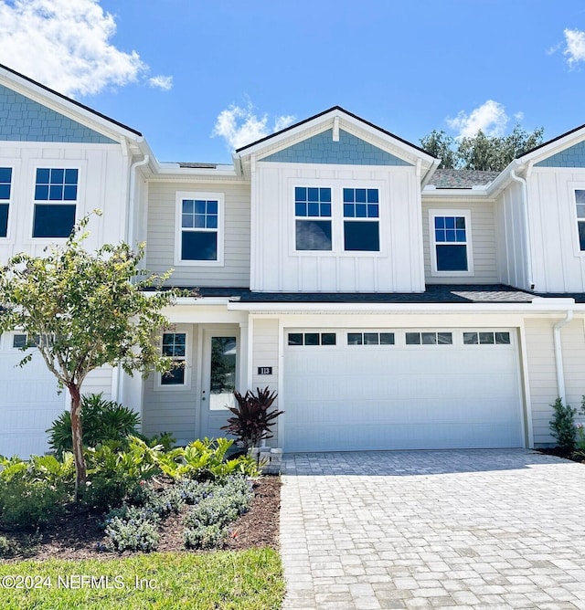 view of front of property with an attached garage, decorative driveway, and board and batten siding