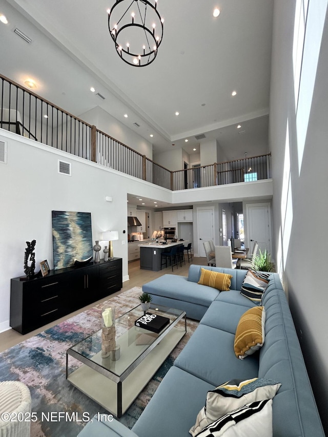 living room featuring a high ceiling, recessed lighting, visible vents, and a notable chandelier