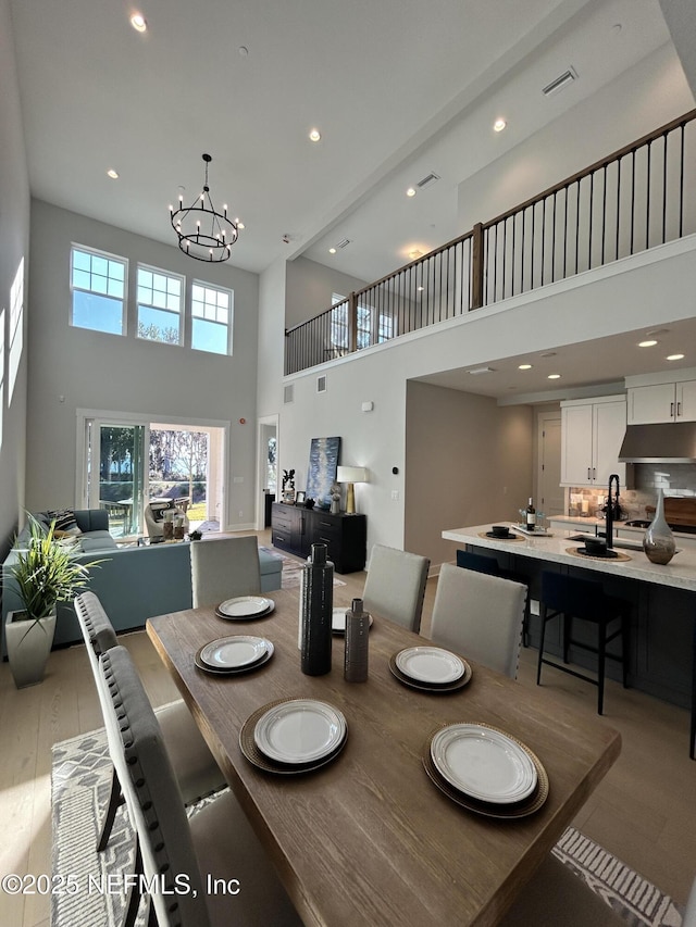 dining area featuring visible vents, a high ceiling, light wood-type flooring, a notable chandelier, and recessed lighting