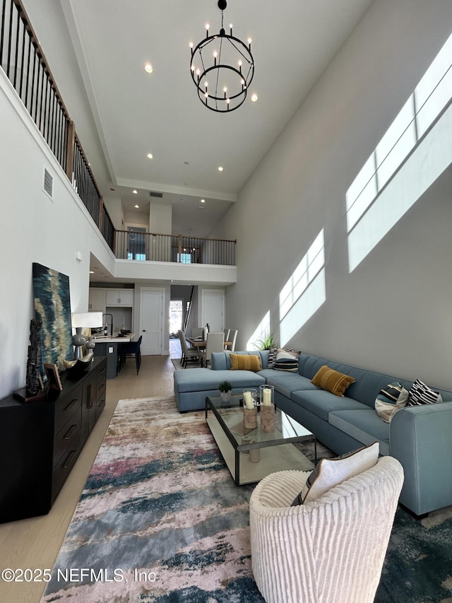 living area featuring visible vents, recessed lighting, a towering ceiling, and an inviting chandelier