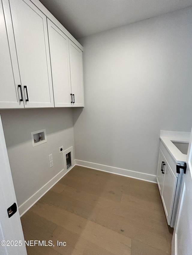 washroom with cabinet space, baseboards, dark wood-type flooring, hookup for an electric dryer, and washer hookup