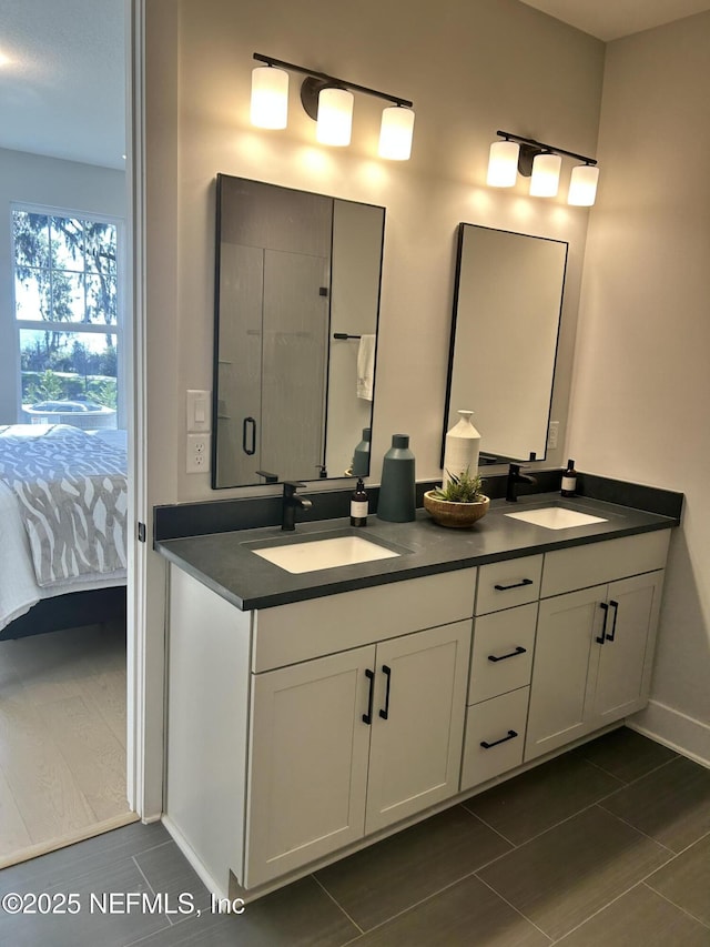 ensuite bathroom with connected bathroom, a sink, baseboards, and double vanity