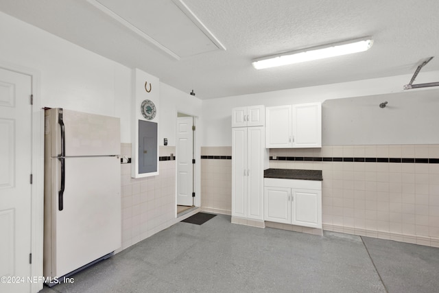 garage featuring electric panel and white fridge