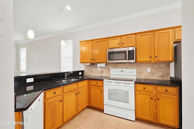 kitchen with dark stone counters, white appliances, crown molding, sink, and decorative light fixtures