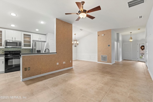 kitchen with stainless steel appliances, pendant lighting, white cabinets, backsplash, and ceiling fan with notable chandelier