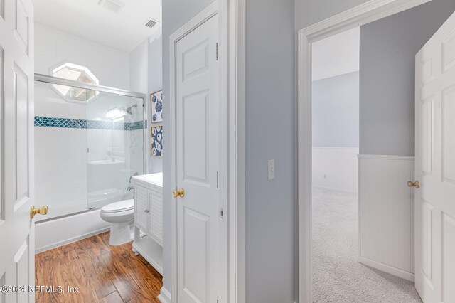 full bathroom featuring toilet, combined bath / shower with glass door, hardwood / wood-style floors, and vanity