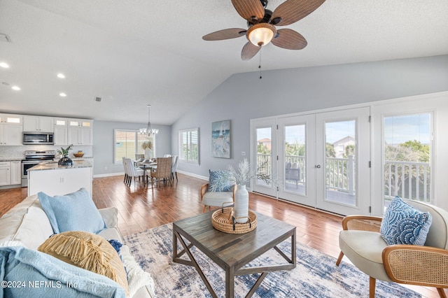 living room featuring french doors, light hardwood / wood-style floors, high vaulted ceiling, and ceiling fan with notable chandelier