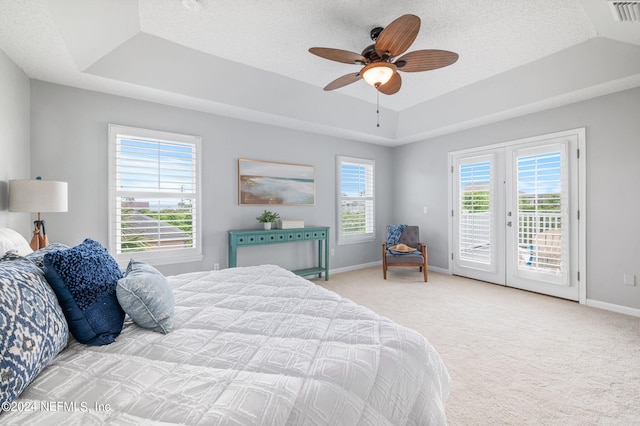 bedroom featuring access to exterior, light carpet, a raised ceiling, a textured ceiling, and ceiling fan