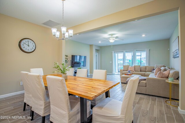 dining space featuring ceiling fan with notable chandelier and hardwood / wood-style flooring