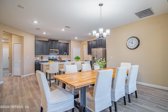 dining space with light hardwood / wood-style flooring, an inviting chandelier, and sink