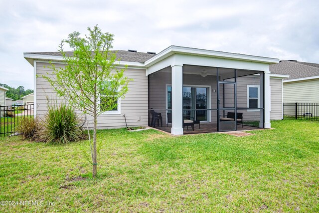 rear view of property featuring a sunroom and a lawn