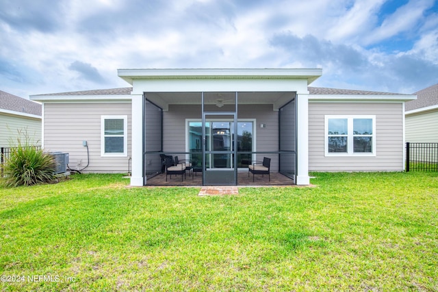 back of property with a sunroom, cooling unit, and a lawn