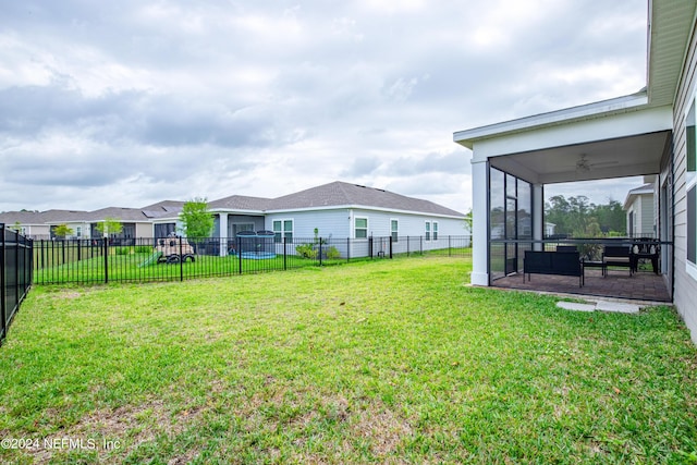 view of yard featuring a sunroom and ceiling fan