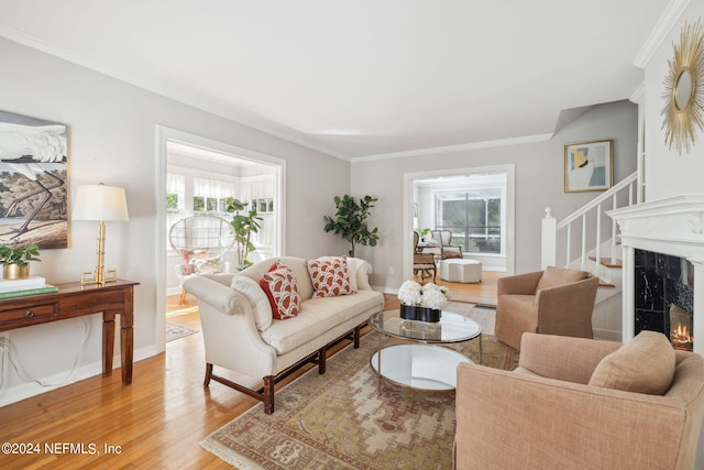 living room featuring crown molding, hardwood / wood-style floors, a high end fireplace, and plenty of natural light