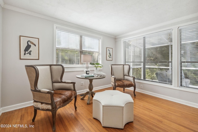 sitting room with light wood-type flooring, plenty of natural light, and crown molding