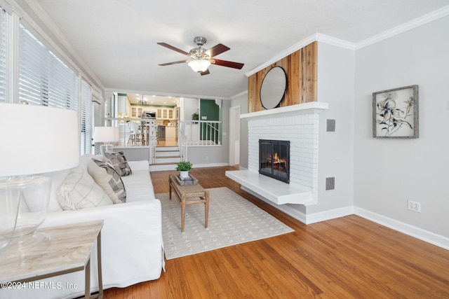 living room featuring ceiling fan, a fireplace, ornamental molding, and hardwood / wood-style flooring