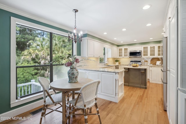 kitchen with stainless steel appliances, light hardwood / wood-style flooring, pendant lighting, decorative backsplash, and white cabinets