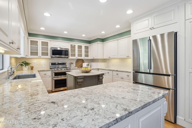 kitchen with light stone countertops, appliances with stainless steel finishes, white cabinetry, and sink