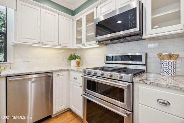 kitchen with appliances with stainless steel finishes, light wood-type flooring, and white cabinetry