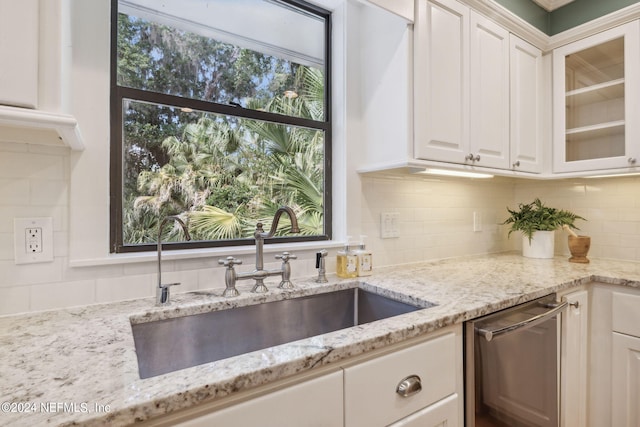 kitchen featuring dishwasher, white cabinets, sink, light stone countertops, and tasteful backsplash