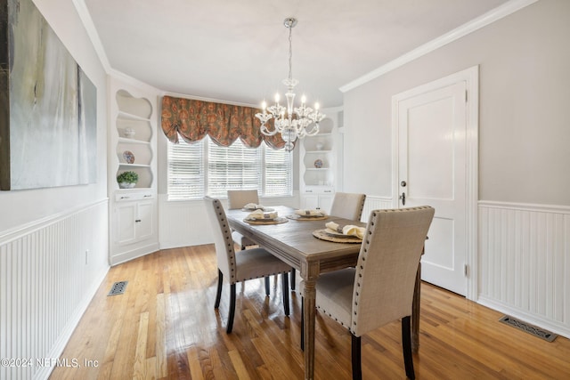 dining area featuring a notable chandelier, built in features, light wood-type flooring, and ornamental molding