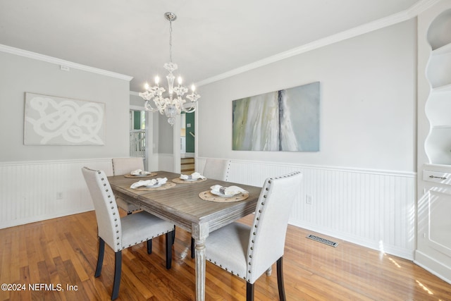 dining space featuring hardwood / wood-style floors, ornamental molding, and an inviting chandelier