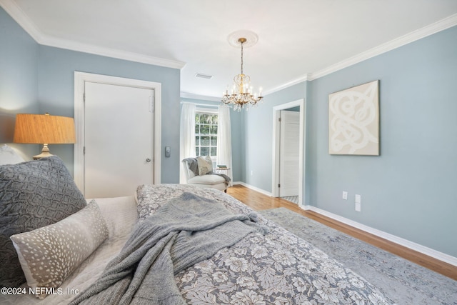 bedroom featuring hardwood / wood-style floors, ornamental molding, and an inviting chandelier