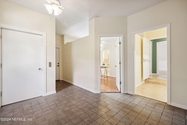 empty room featuring ceiling fan, light tile patterned flooring, and a textured ceiling