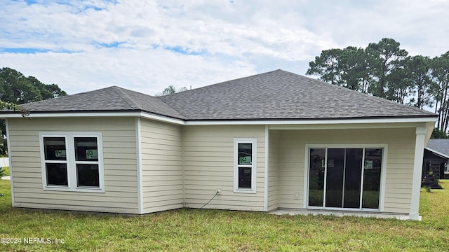 rear view of property featuring a shingled roof and a yard