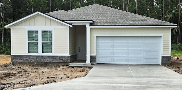 ranch-style home featuring an attached garage, stone siding, driveway, roof with shingles, and board and batten siding