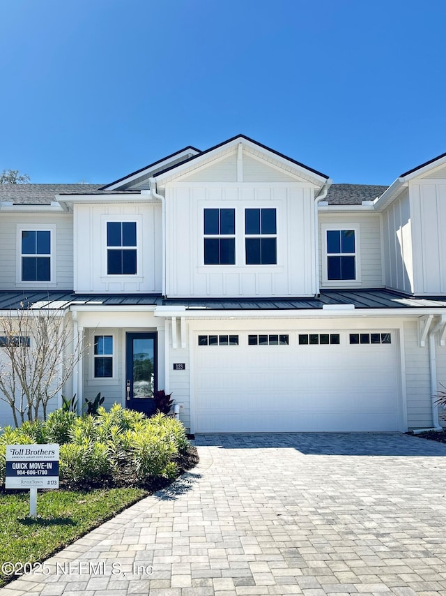 modern farmhouse style home featuring decorative driveway, board and batten siding, and an attached garage