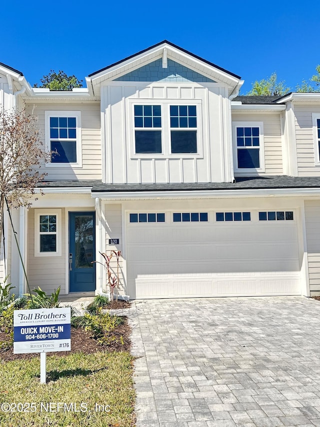 view of front of house featuring board and batten siding, decorative driveway, and a garage