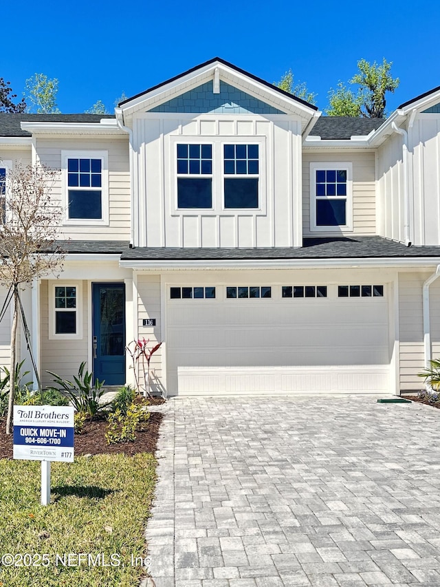 view of front facade with board and batten siding, an attached garage, and decorative driveway