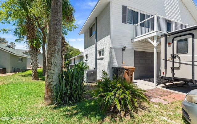 view of side of property with a yard, a garage, a balcony, and central air condition unit