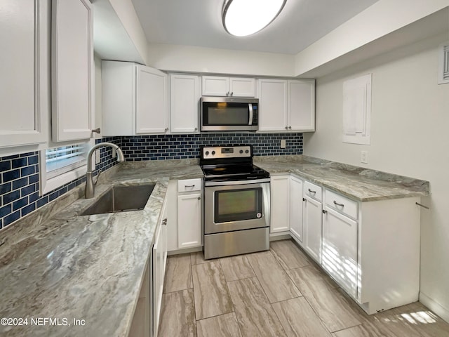 kitchen with light stone counters, white cabinets, sink, tasteful backsplash, and stainless steel appliances