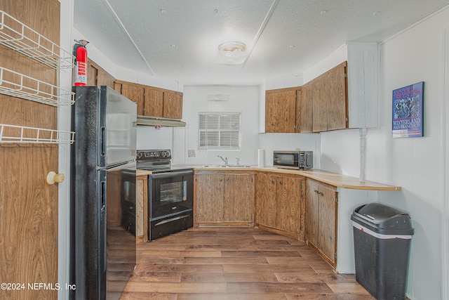 kitchen with wood-type flooring, sink, black appliances, and a textured ceiling