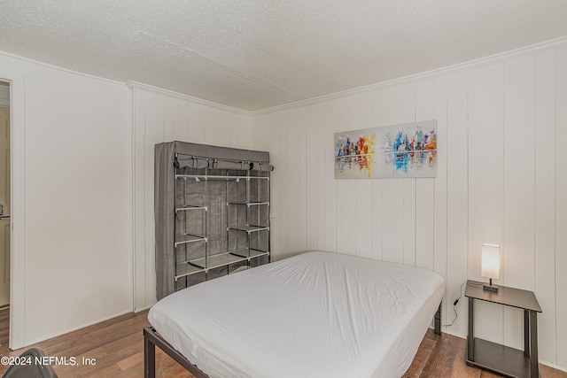 bedroom with crown molding, a textured ceiling, and wood-type flooring